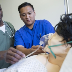 Students practicing medical procedure on a medical mannequin.