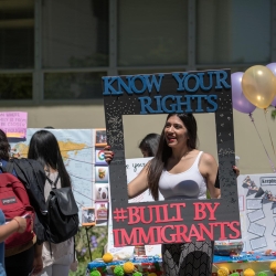 Student holding a poster that says "know your rights" above a cutout framing the student and "built by immigrants" below.